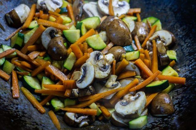 Wok sur plaque à induction Légumes sautés dans un wok en acier sur une plaque à induction